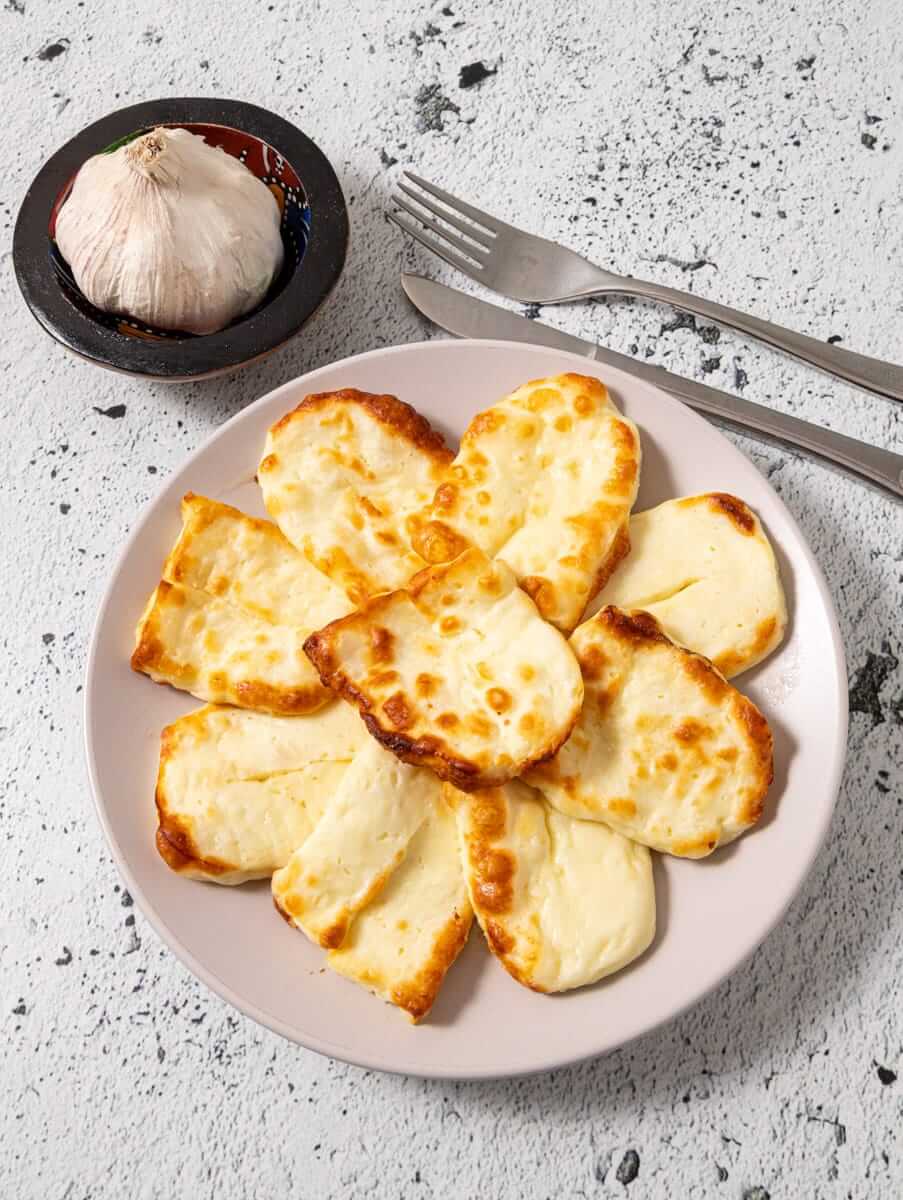 Air fried halloumi slices on a plate with garlic seasoning.