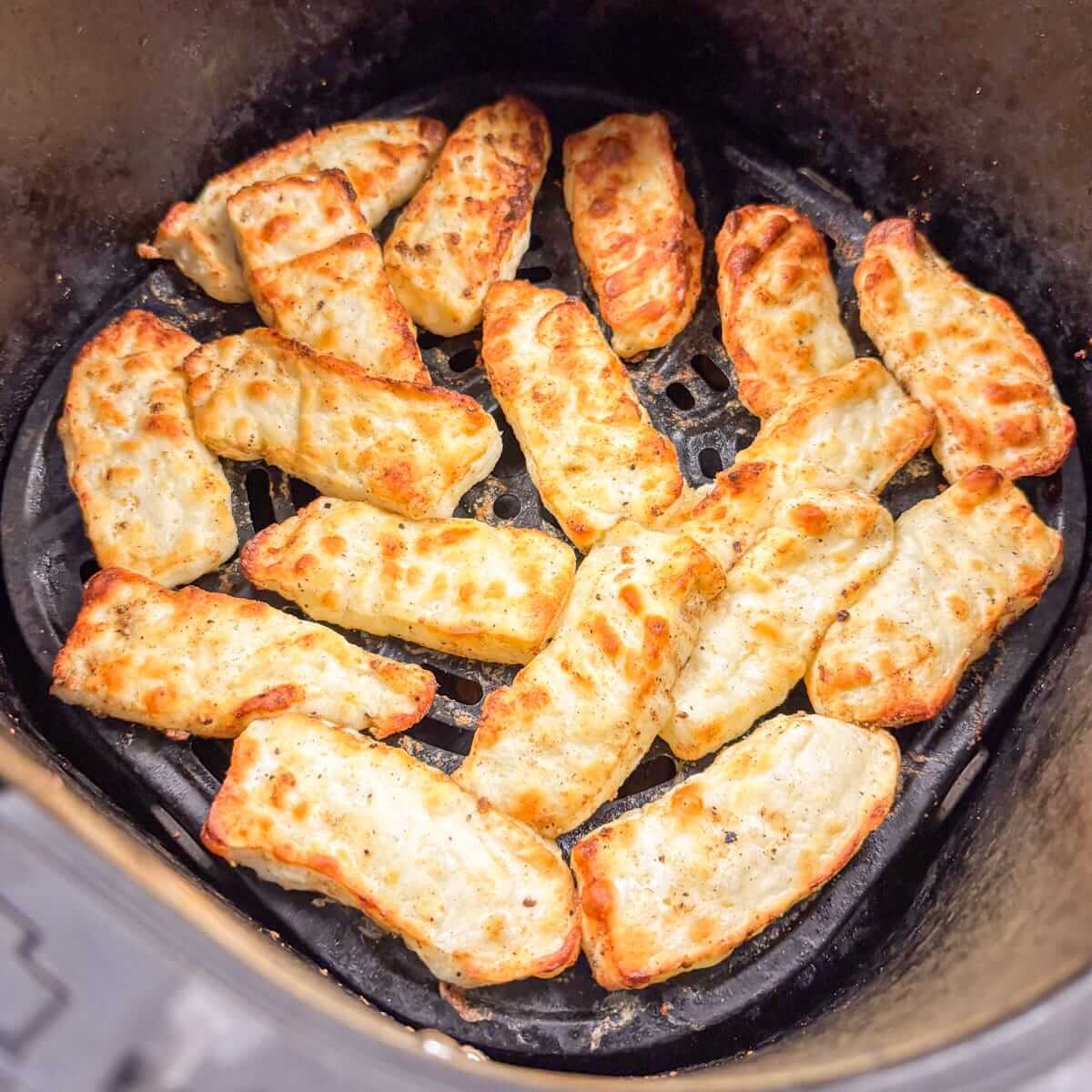 Golden brown roasted halloumi slices in an air fryer.