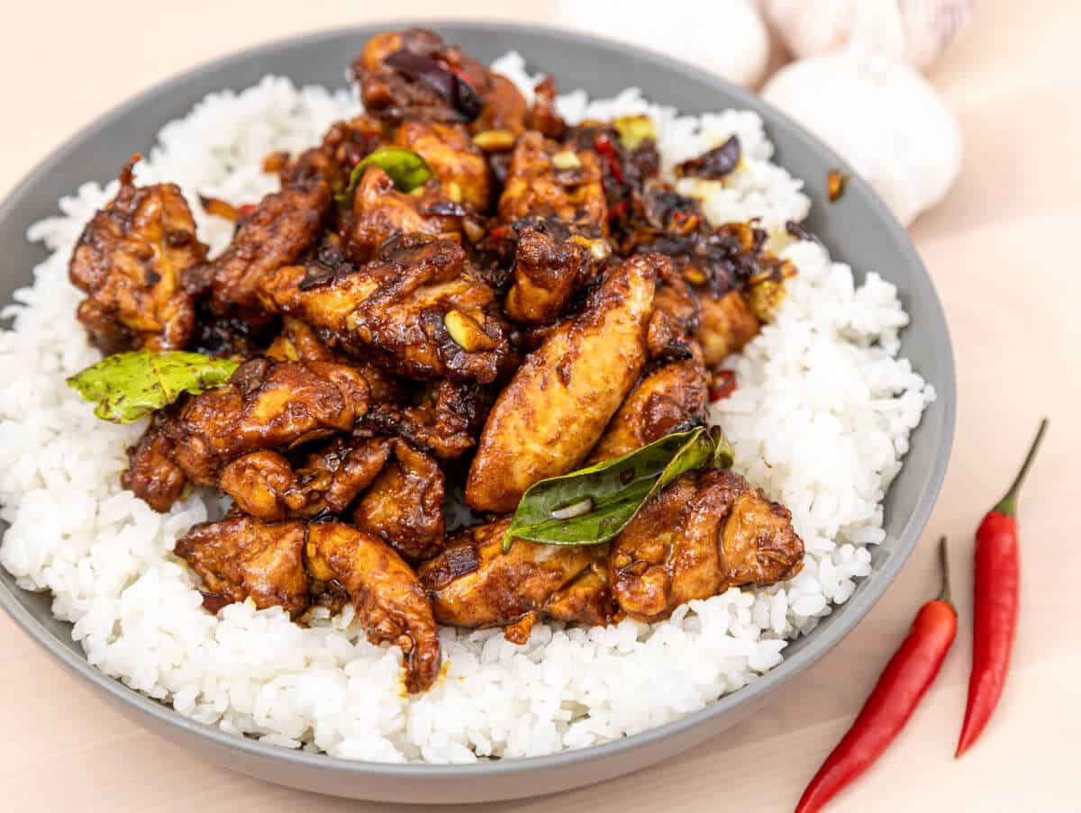 Kam heong chicken over rice in a large bowl.