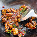 Kam heong chicken is pan fried in a wok.